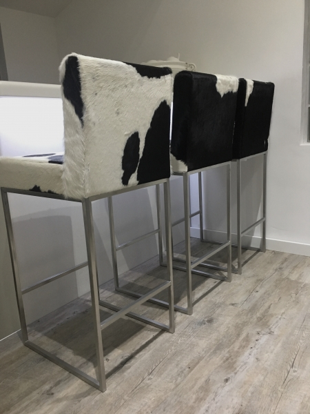 black and white cowhide stools with backs and steel frames.