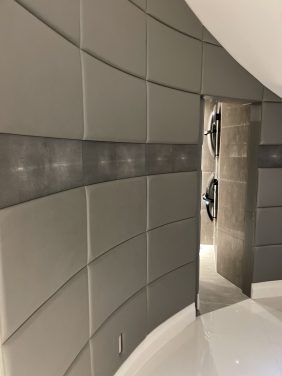 Leather wall panes covering curving wall and door.