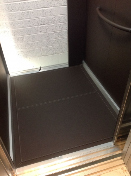 Leather lift car panels on walls and floor.